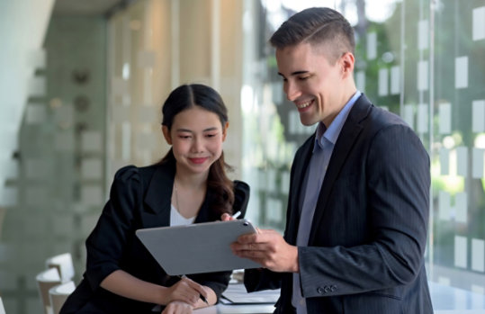 Dos personas miran una tableta mientras una señala el contenido.