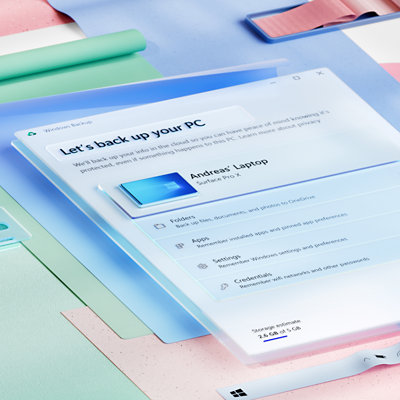 An angled view of the Windows Backup app showing options to back up a PC with light coloured sheets of paper layered behind it