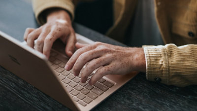man in yellow dress shirt using Microsoft Surface Laptop