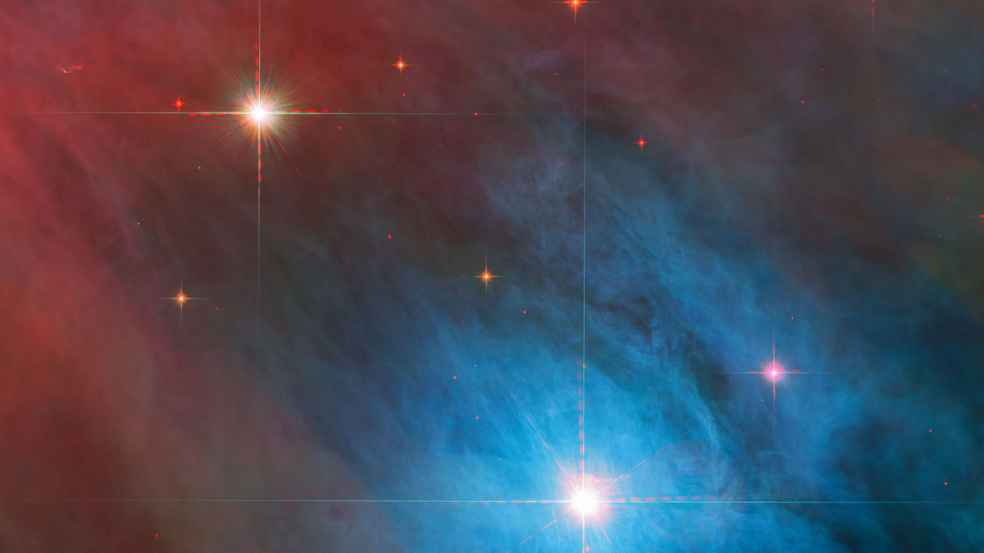 The bright star V 372 Orionis and its companion are captured in this new Hubble image, surrounded by large cross-shaped diffraction spikes. Small red stars with shorter diffraction spikes are scattered around them, against a background of red and blue gas clouds. 