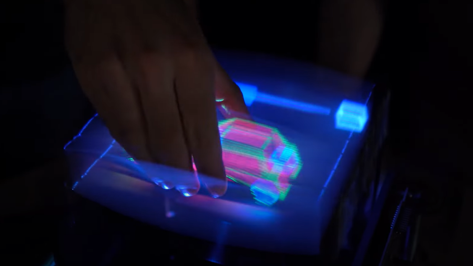 Person uses hand to grab a hologram of a red car.