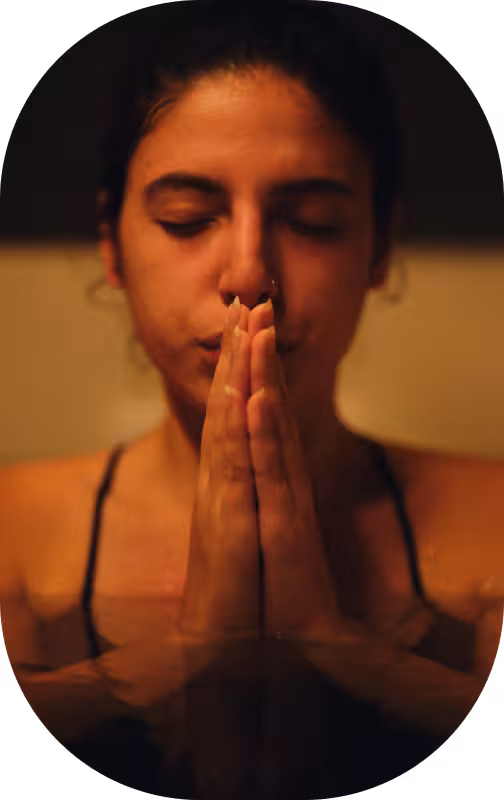 A woman with her hands placed together in a meditative pose.