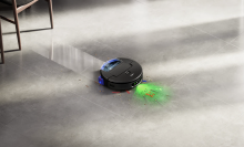 Dyson Spot+Scrub Ai robot vacuum mopping floor with kitchen chairs in peripheral view