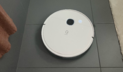 Yeedi robot vacuum cleaning gray tile floor between shower curtain and bath mat