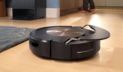 Roomba Combo j9+ mopping hardwood floor with dock and person's feet in background