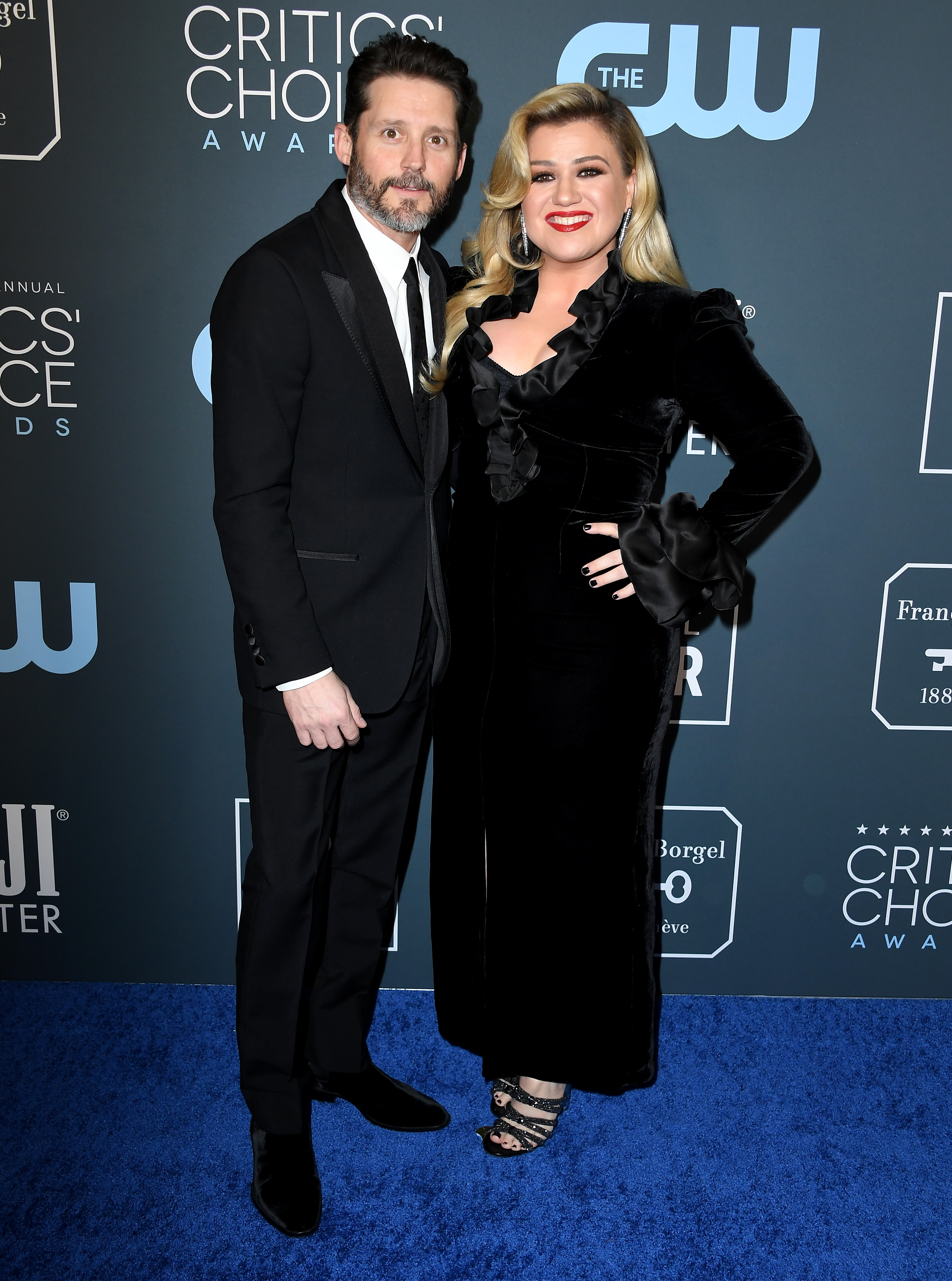 Brandon Blackstock in a black suit, white shirt and black tie, Kelly C
Clarkson in a black velvet coat with frills.