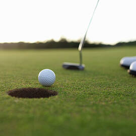 Golf Ball At Edge Of Hole On Green by Dougal Waters