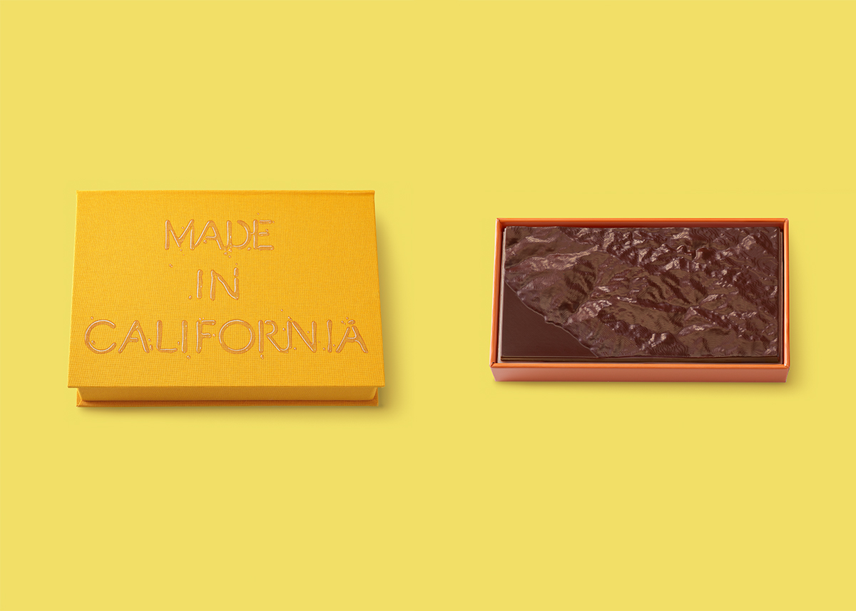 a yellow box on the left that says "Made in California" on the lid, with a textured chocolate bar on the right, both on a yellow background