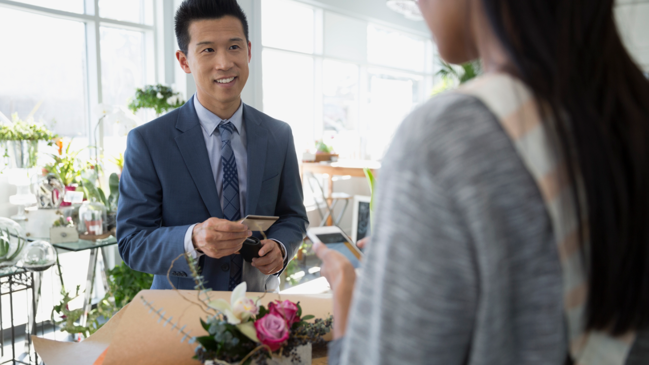 Man paying florist for bouquet in flower shop