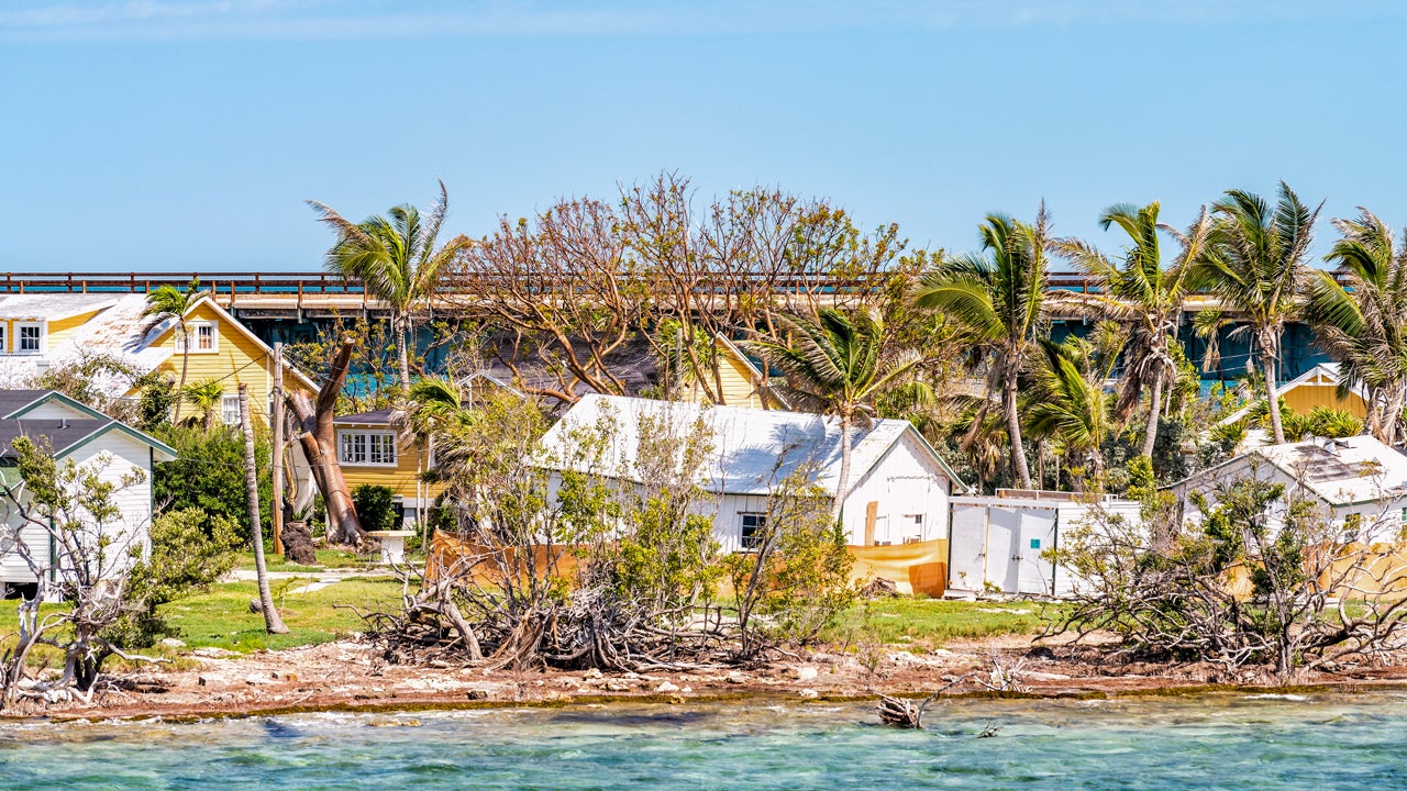 A home on the coast that has been damaged by a hurricane. It is a sunny day.