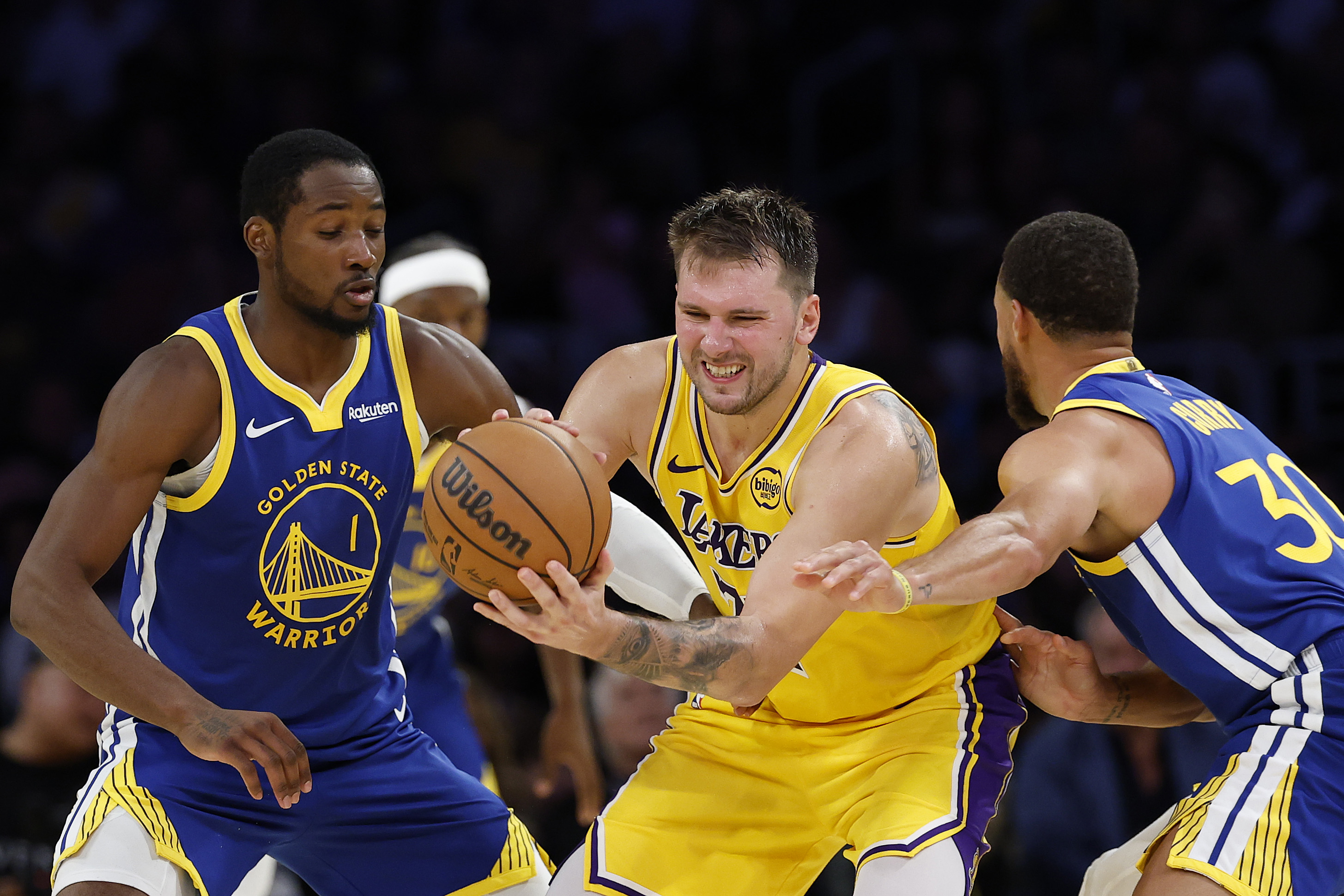 Lakers star Luka Doncic, center, is trapped by the Golden State Warriors’ Jonathan Kuminga, left, and Steph Curry during the fourth quarter of their season opener on Tuesday night at Crypto.com Arena. (Photo by Harry How/Getty Images)
