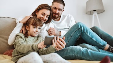 A video preview screen of a family of three huddled around a tablet.