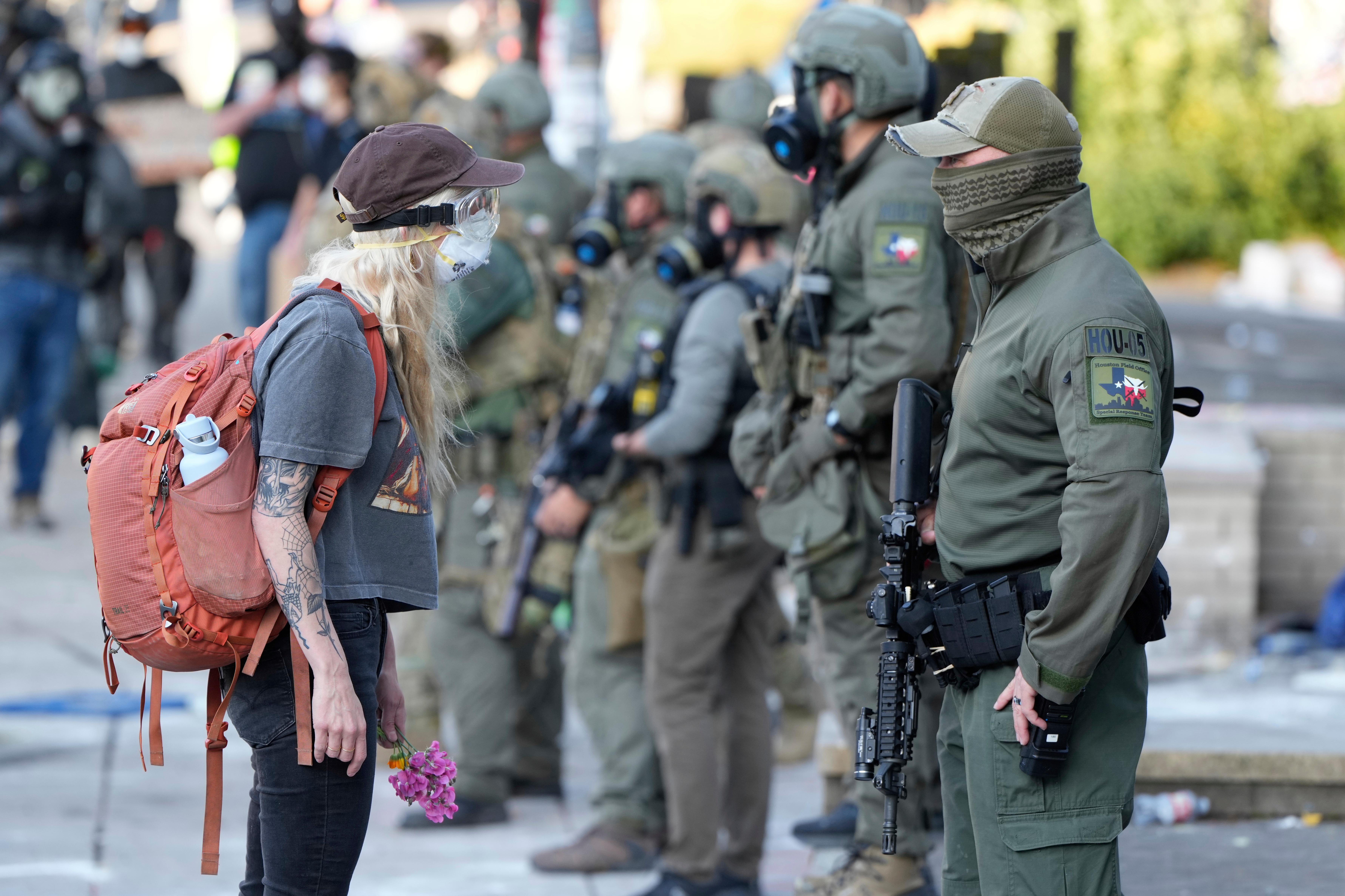 FILE – A woman stands off with a law enforcement officer wearing a Houston Field Office Special Response Team patch outside the U.S. Immigration and Customs (ICE) building during a protest Saturday, June 14, 2025, in Portland, Ore. (AP Photo/Jenny Kane, File)
